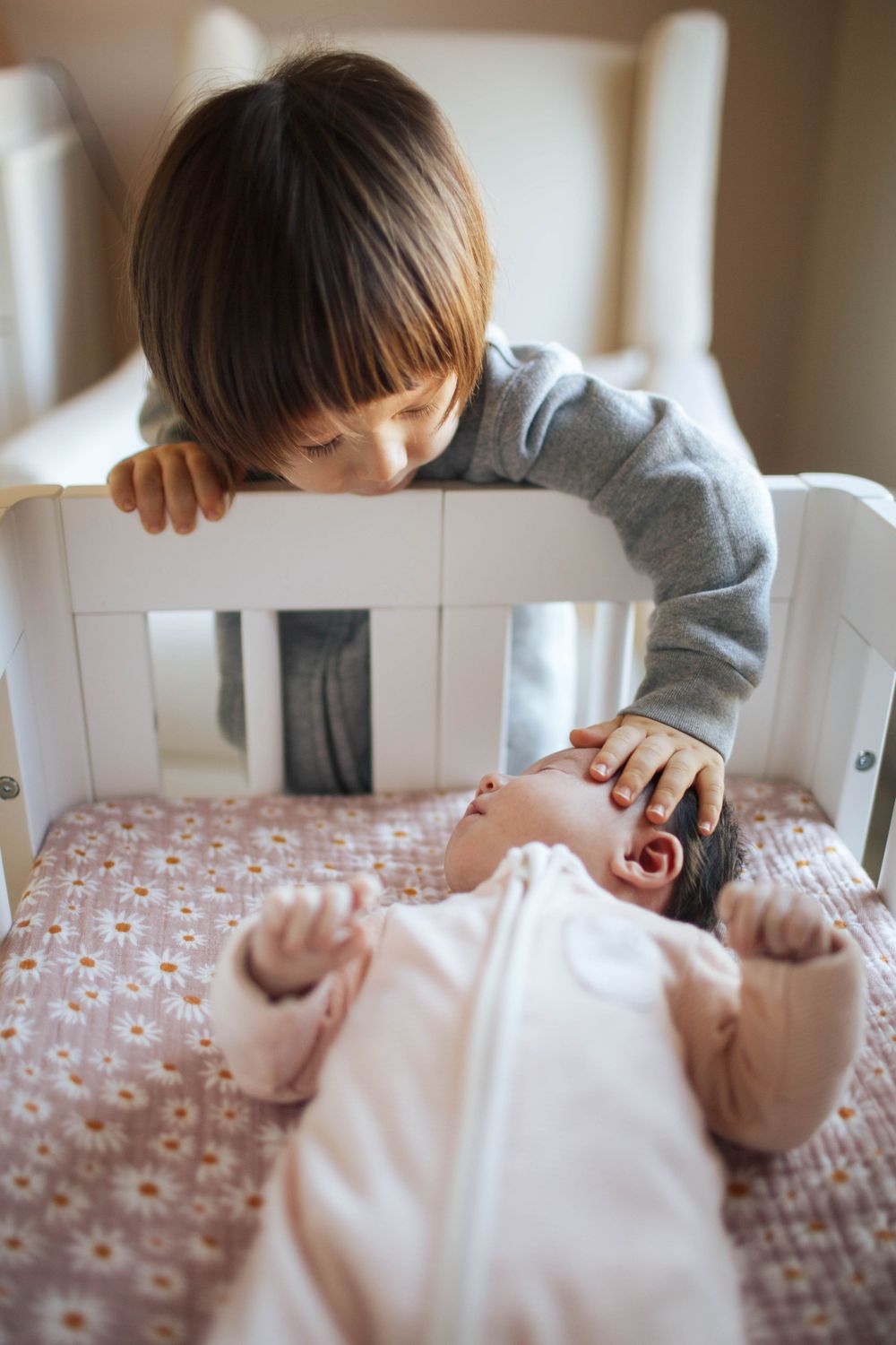 Everett WA newborn photography: a toddler touches his newborn baby sister at an in-home newborn photo session