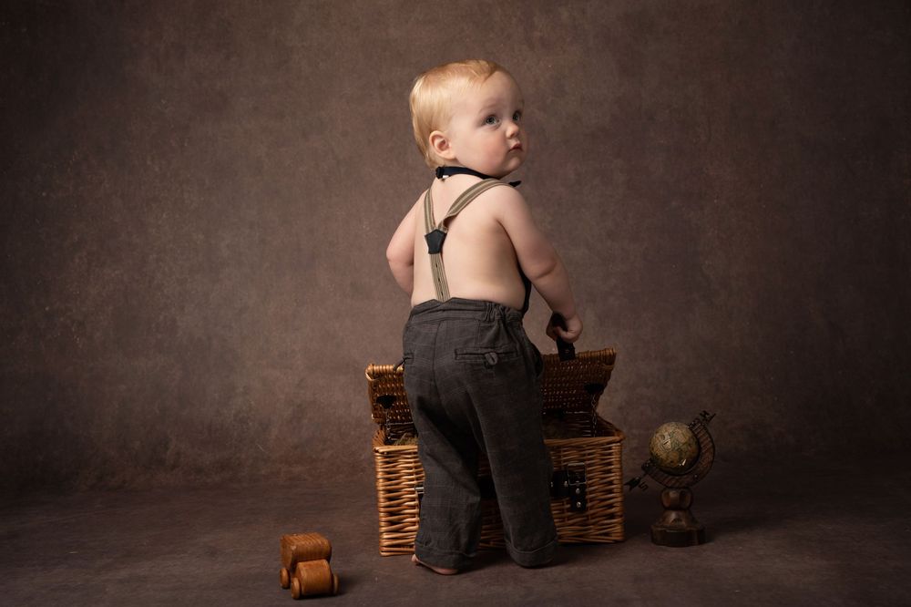 A baby sits among stacks of pennies in a dark studio setting, creating a powerful financial concept image.