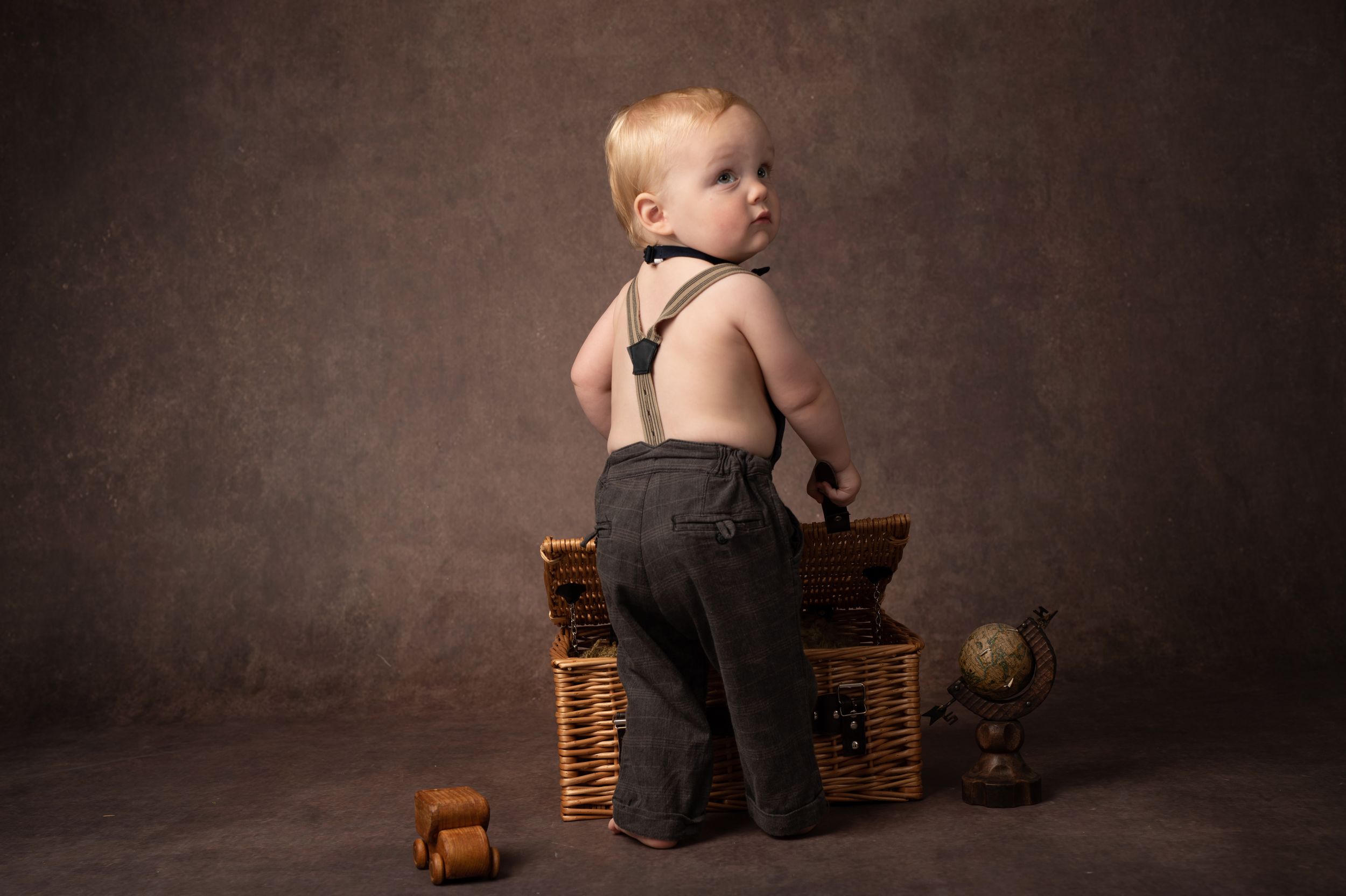 A baby sits among stacks of pennies in a dark studio setting, creating a powerful financial concept image.