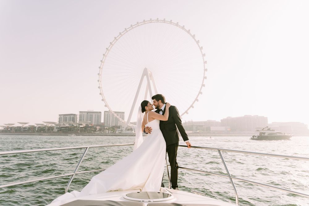 A romantic couple in wedding attire sharing a moment on a boat with the Singapore Flyer observation wheel in the background.