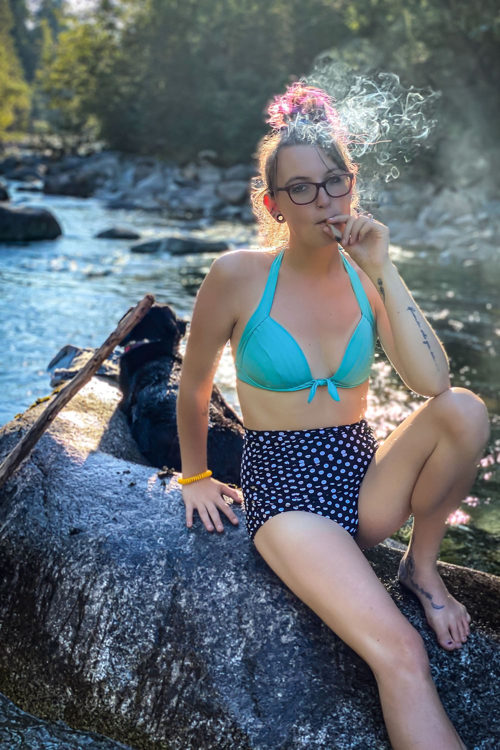 Person in vintage style swimwear poses on rocks by a river.
