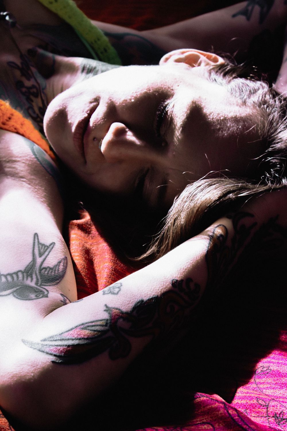 Person sleeping peacefully on a bed with visible tattoos.