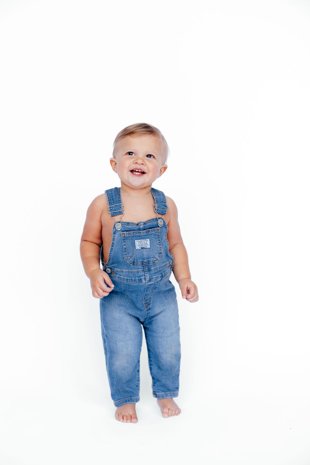 Adorable baby wearing classic blue denim overalls in three different poses against white background.