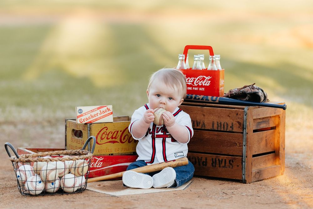 Vintage Coca-Cola crates and collectibles arranged with baseball items in a nostalgic outdoor setting.