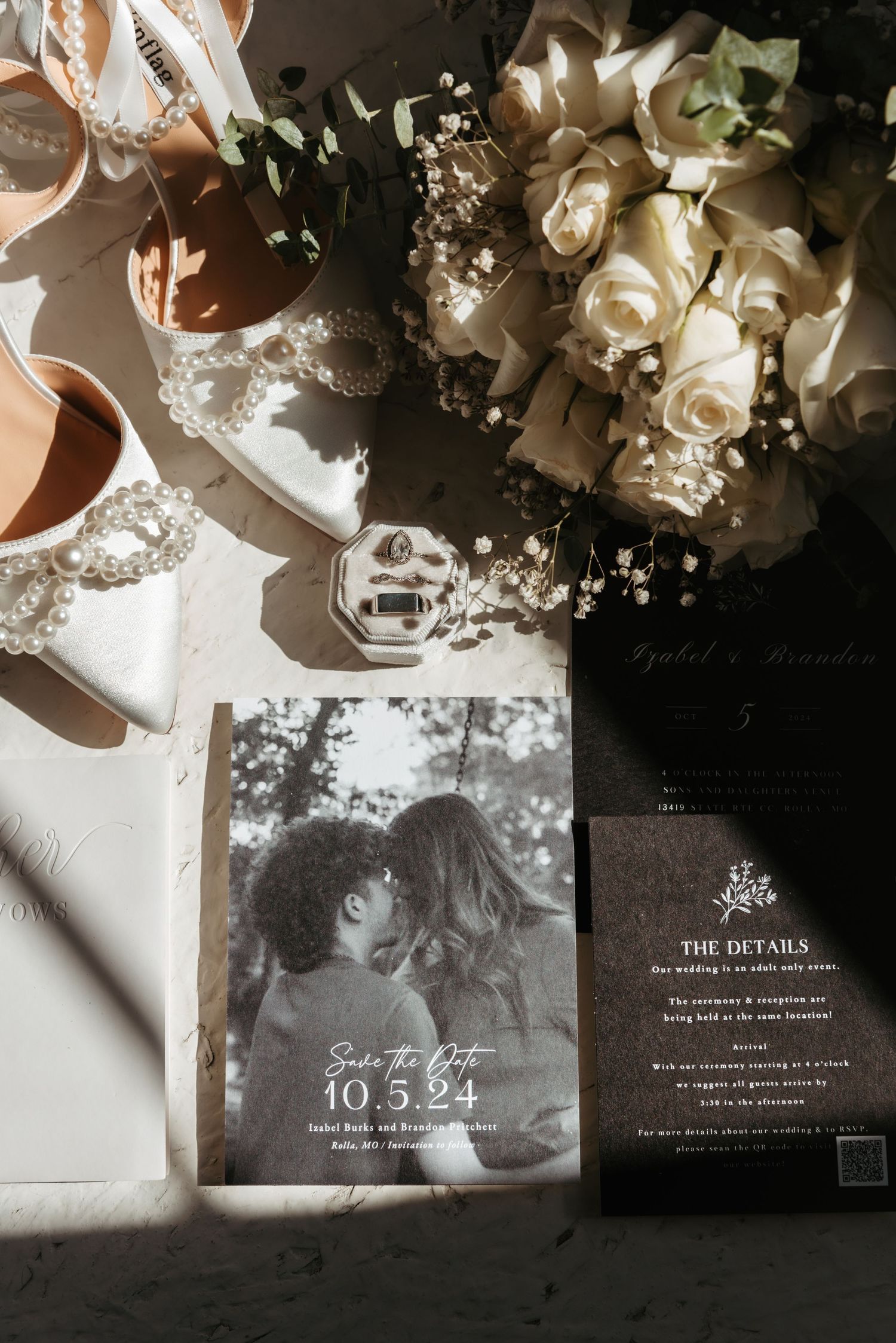 Elegant wedding invitations and floral details arranged with white roses on light background.