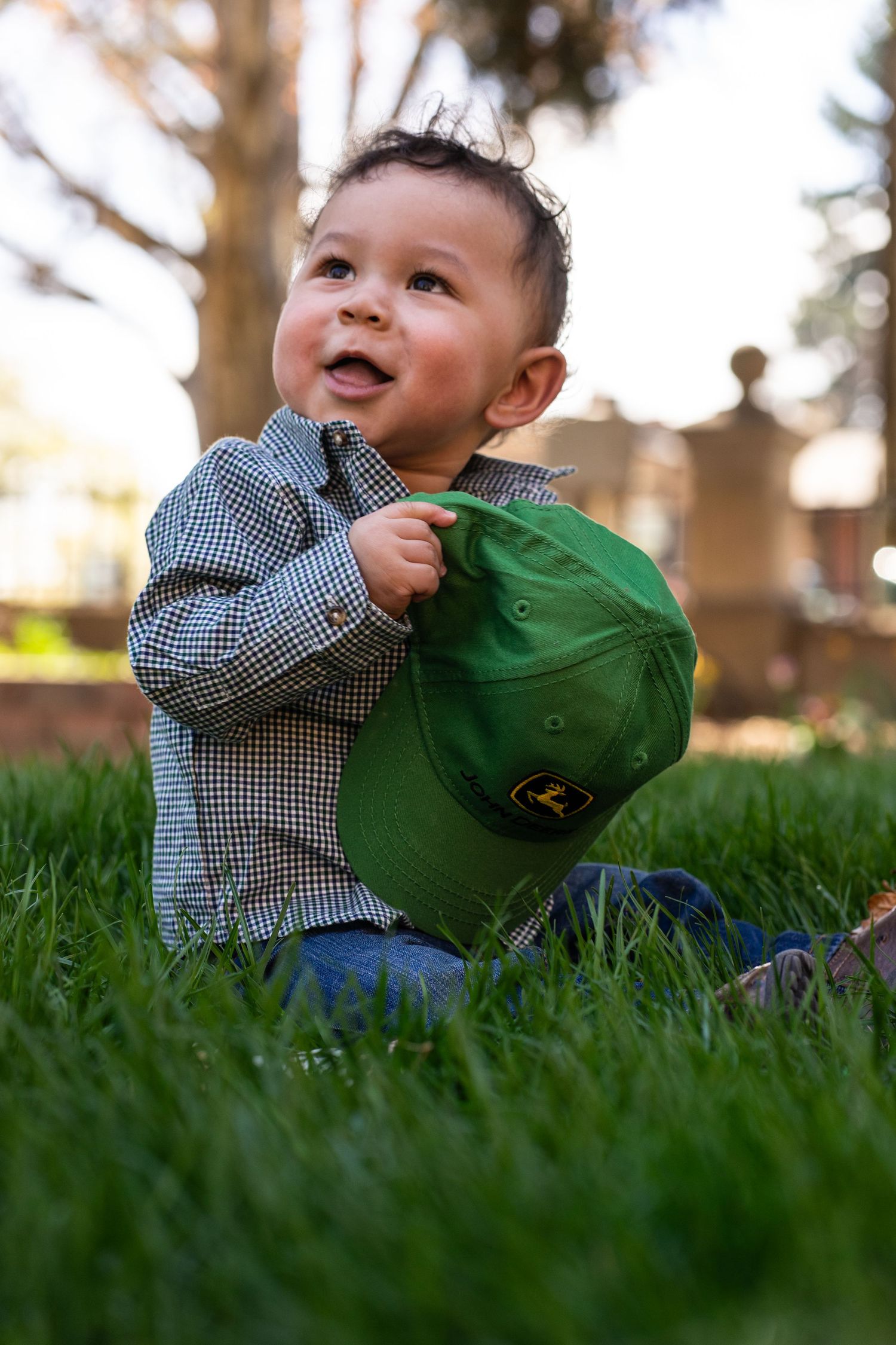 Portrait of a baby sitting in the grass with a John Deere hat