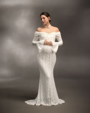 Elegant off-shoulder white lace mermaid wedding gown with long bell sleeves and a fitted silhouette.