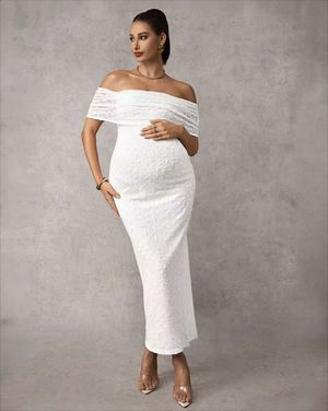 White off-shoulder lace maternity midi dress with fitted silhouette, worn with clear heels.