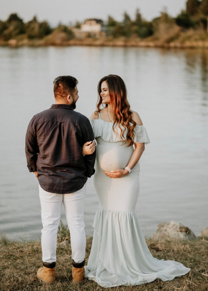 Couple sitting by lakeside in casual attire during golden hour.