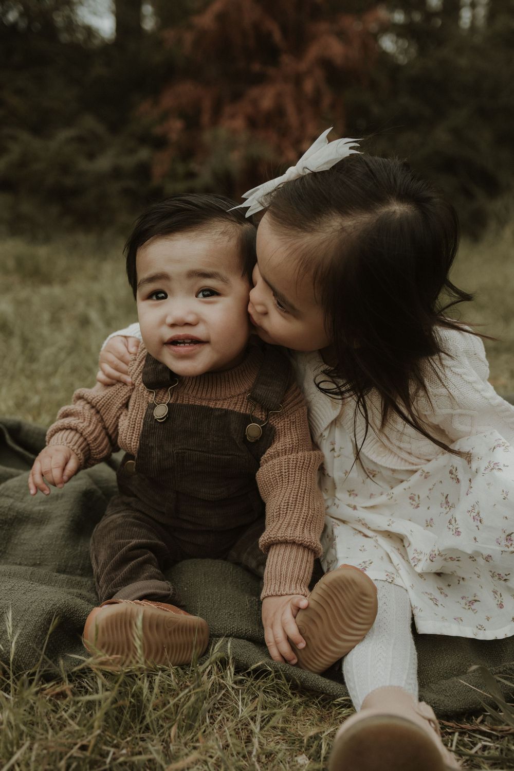 A sweet moment captured in a series of photos showing a parent and child laying in grass together during an outdoor photo session.