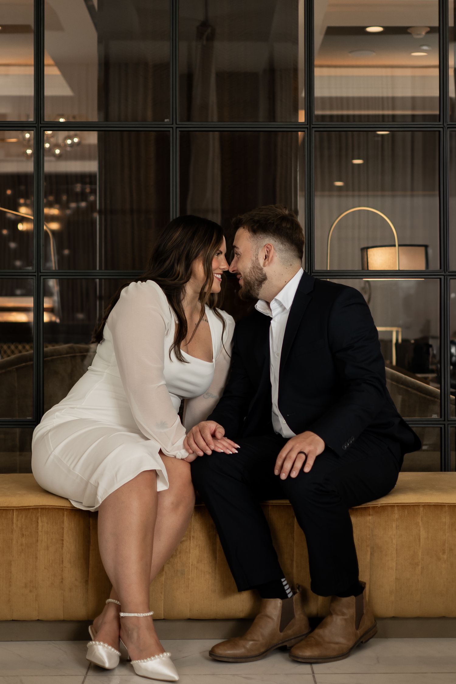 An intimate couple shares a tender kiss in a lush garden filled with vibrant flowers and greenery.