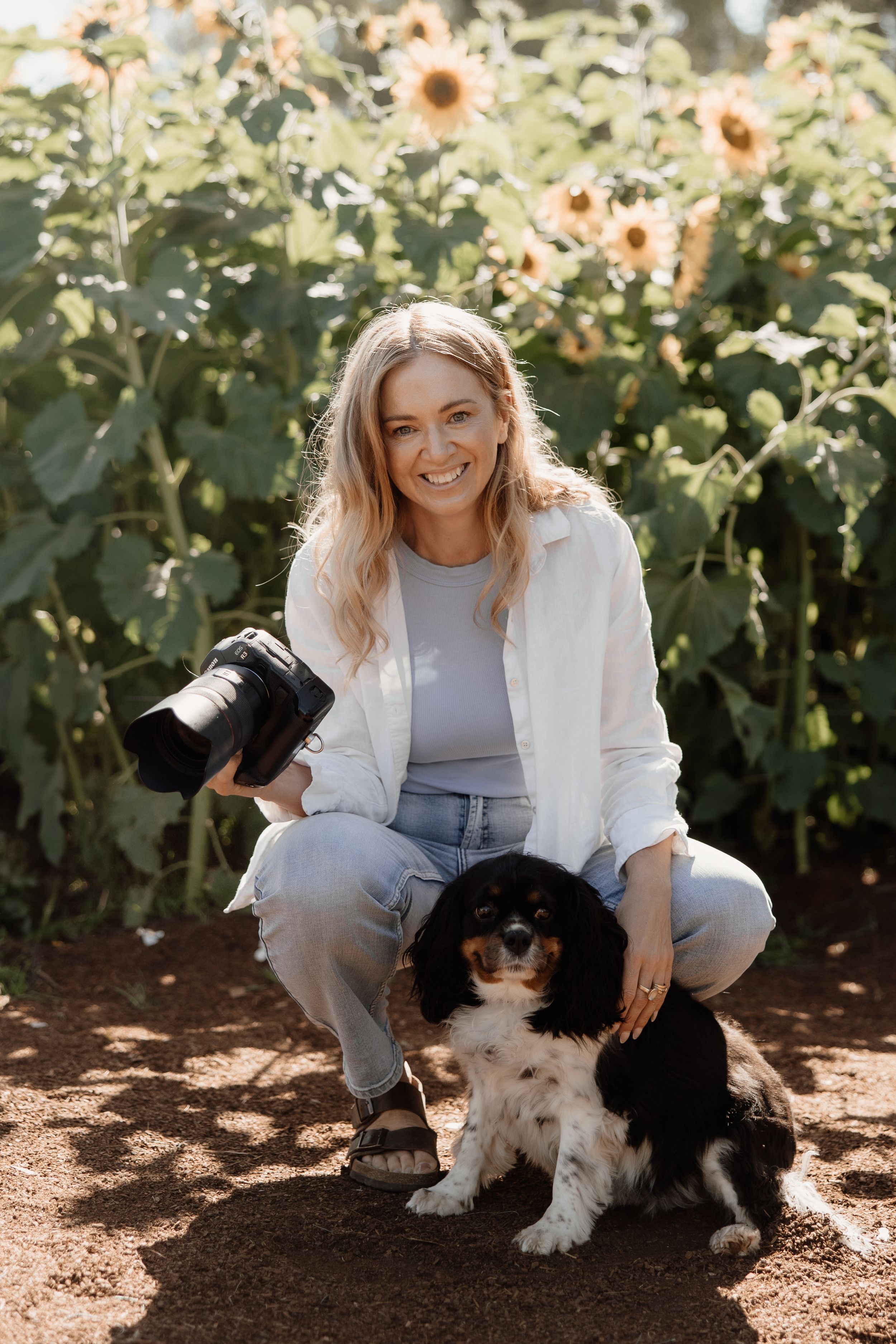 Portrait of professional photographer smiling while holding camera against neutral background.