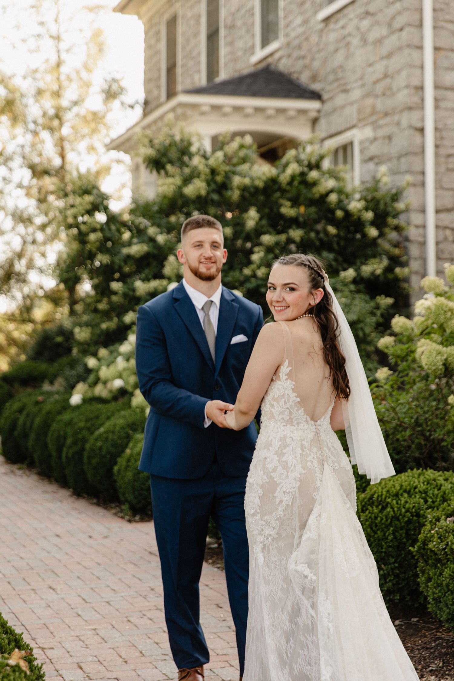 Romantic wedding couple portraits on a stone path surrounded by manicured gardens.