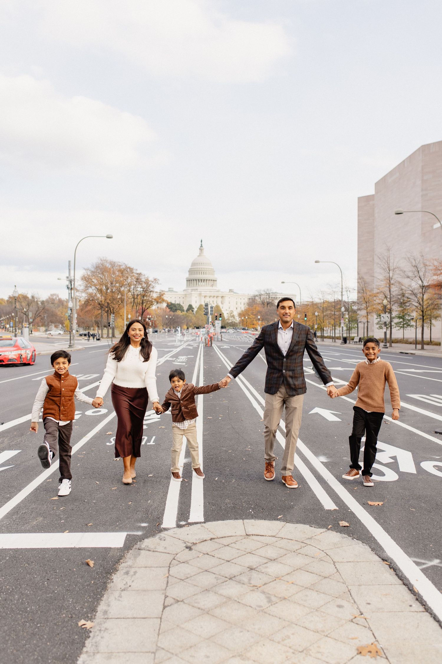 A group jumping and posing playfully on a city street with the Capitol building in the background.