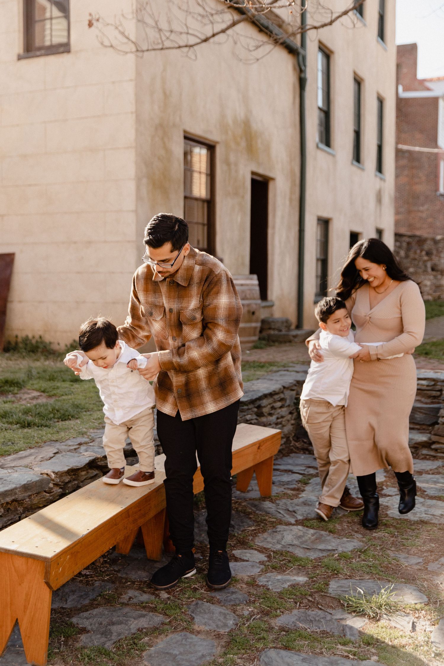 Family enjoying time together in a courtyard with a wooden bench.