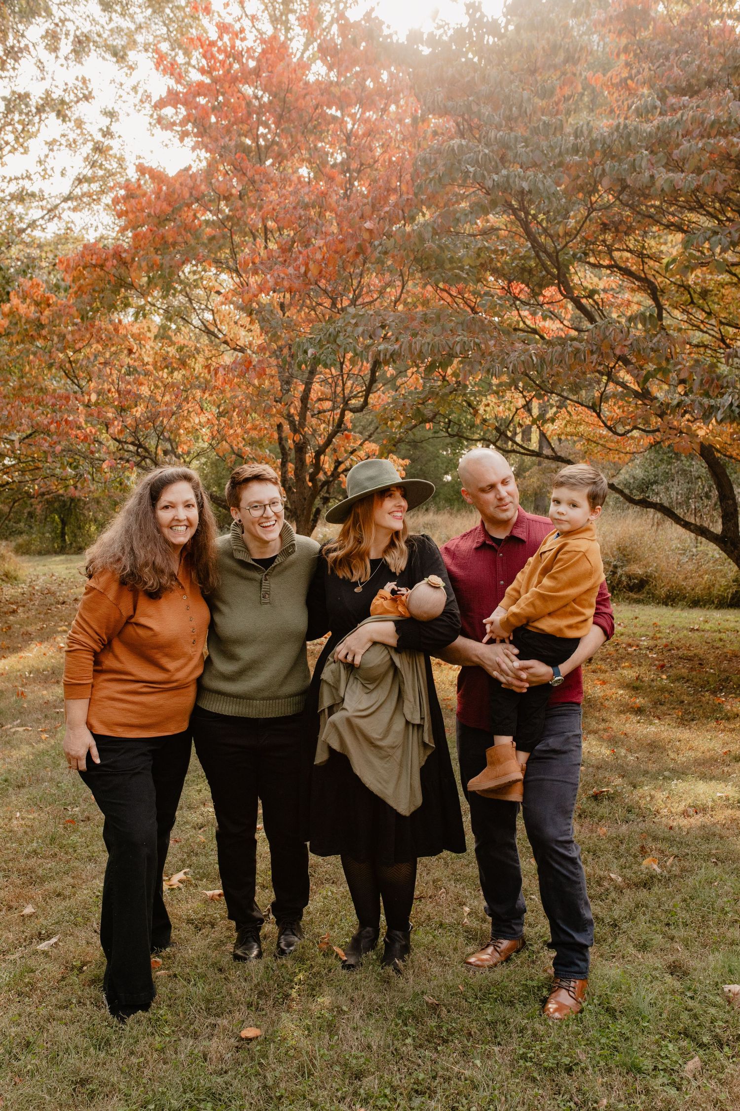 Group poses together outdoors against vibrant autumn foliage on a fall day.