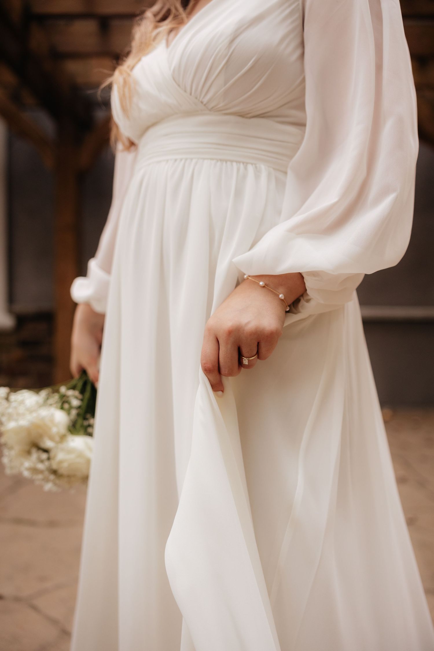 Detail shot of flowing white wedding dress with bishop sleeves and empire waist.