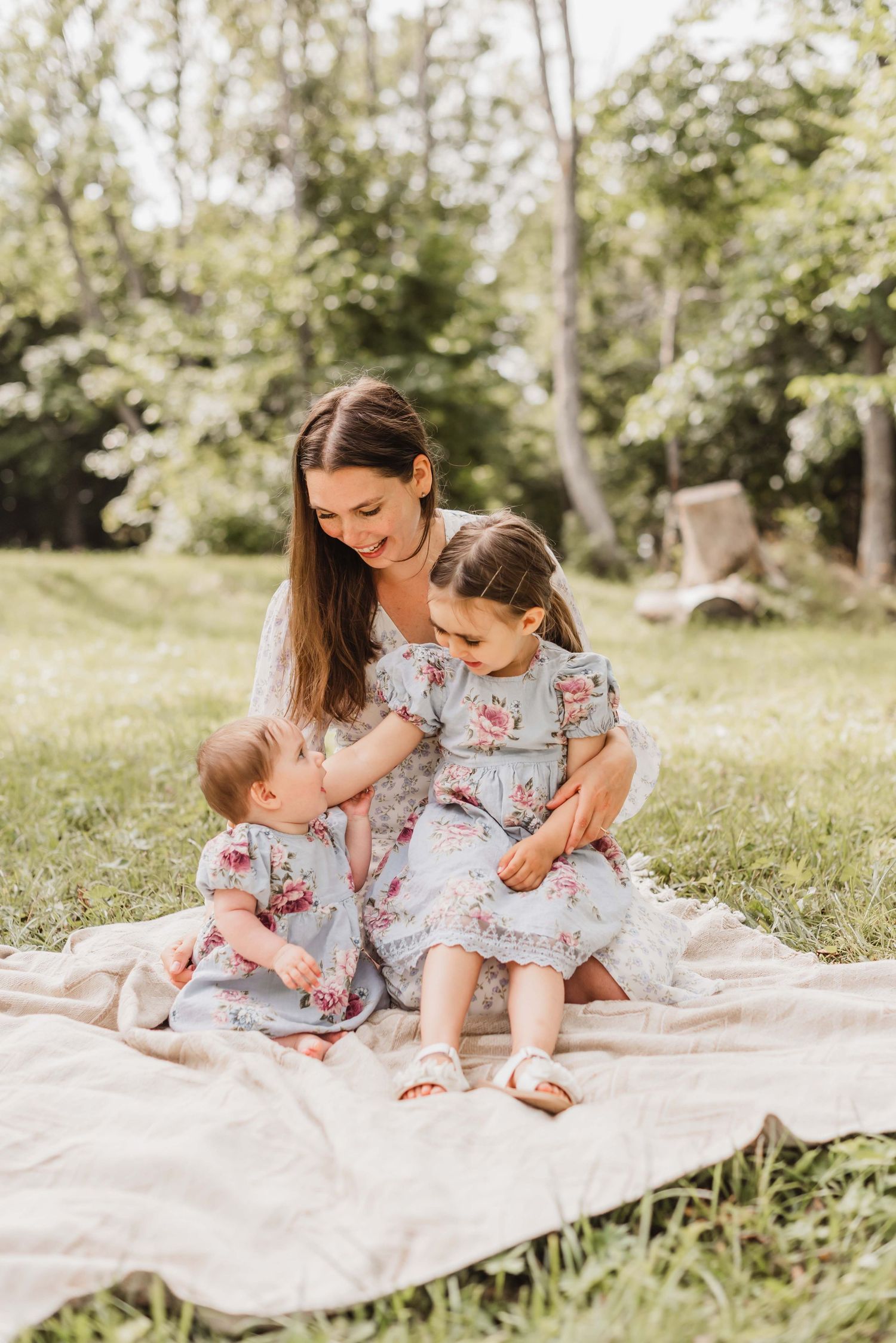A cheerful outdoor portrait with small baby against an olive tree background.
