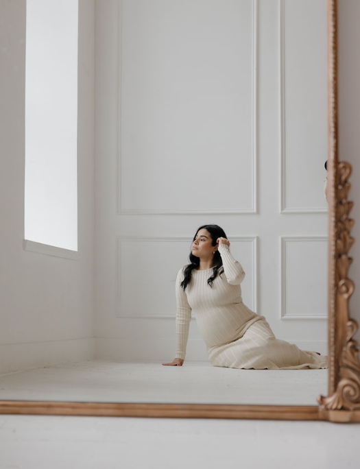 Minimalist maternity photo in white room with natural window light.