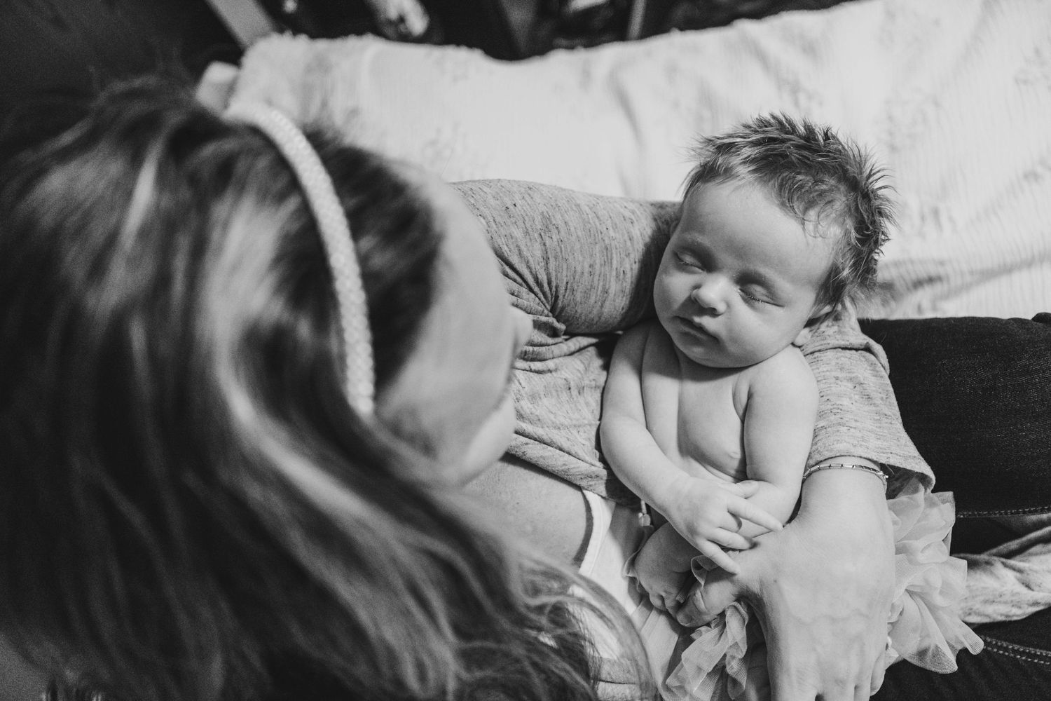 Black and white photo showing a tender moment between parent and baby lying down together.