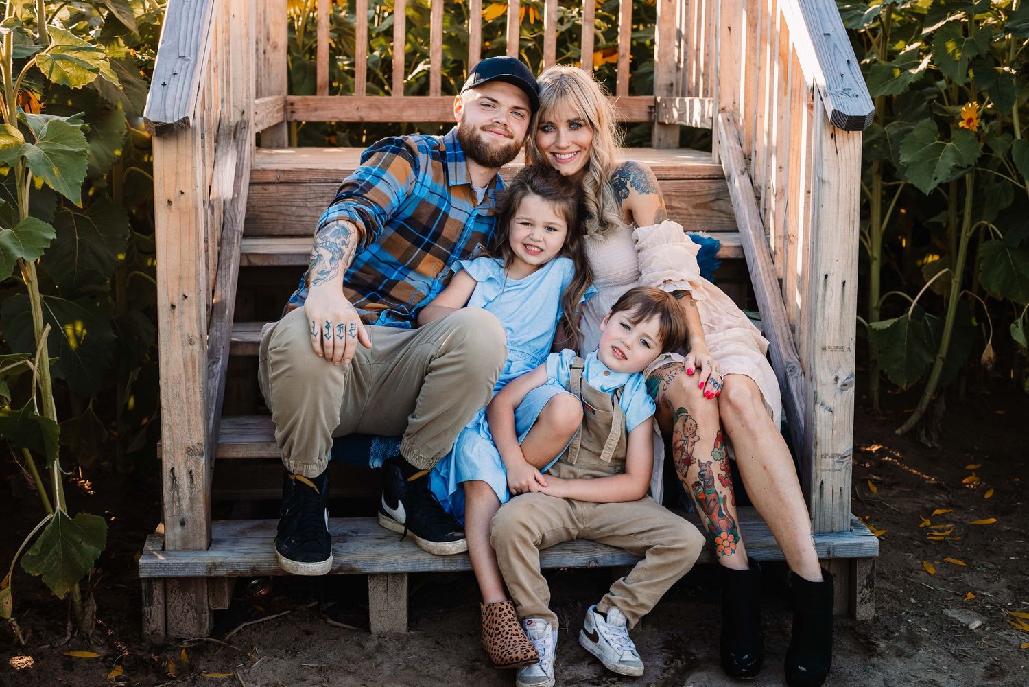 A family of four sitting close together on wooden stairs outdoors.