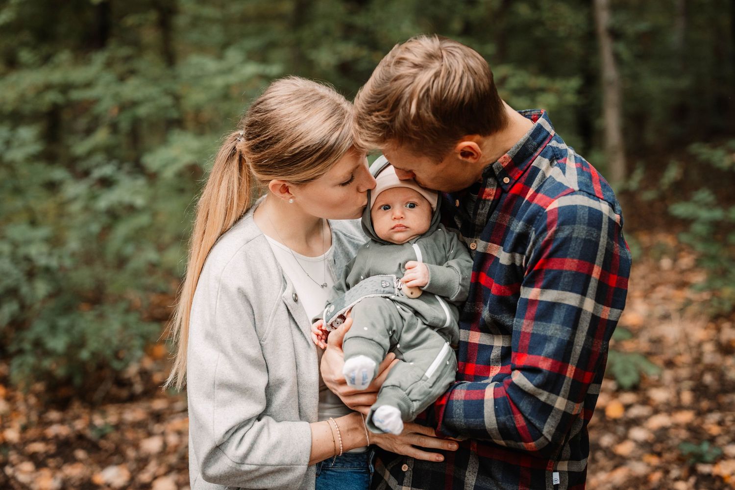 Family shares intimate moment during autumn forest photoshoot.