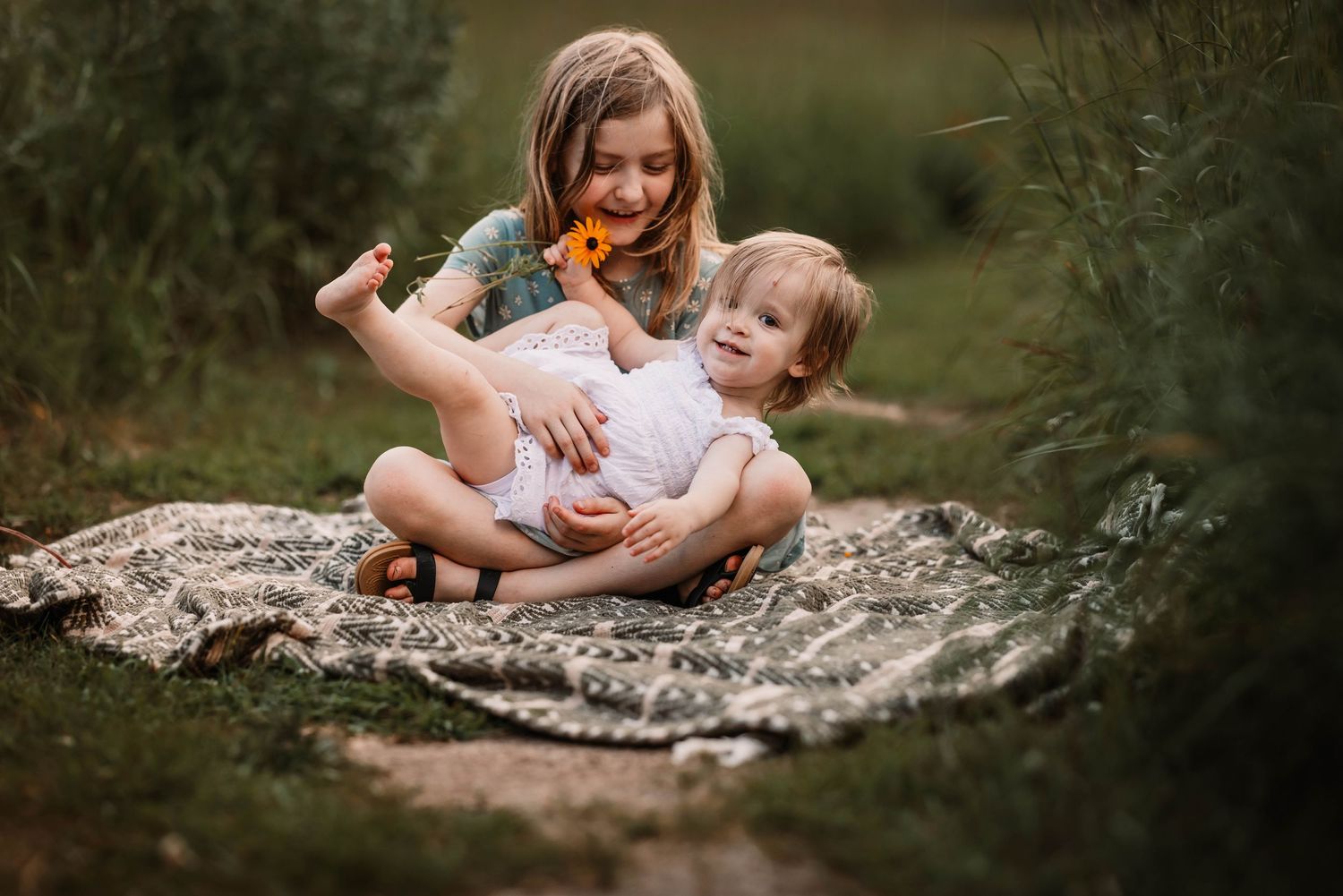 Playful moment between parent and child on picnic blanket outdoors.