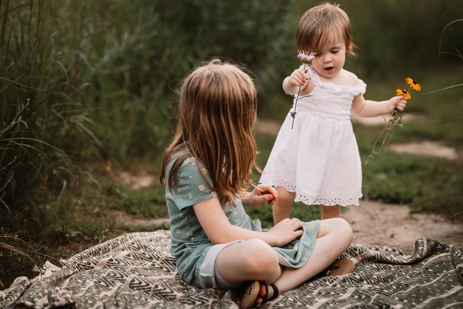 Two children sitting on rock sharing special moment with yellow flower.