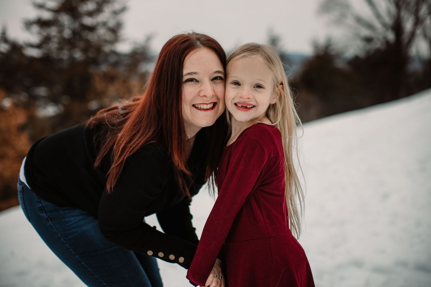 A sweet moment captured between two people in the snow with autumn colors in the background.