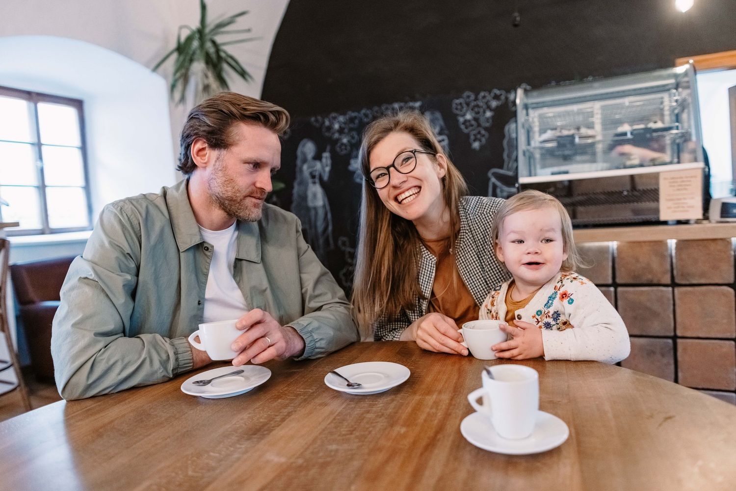 Family enjoying coffee and treats together at casual cafe setting.