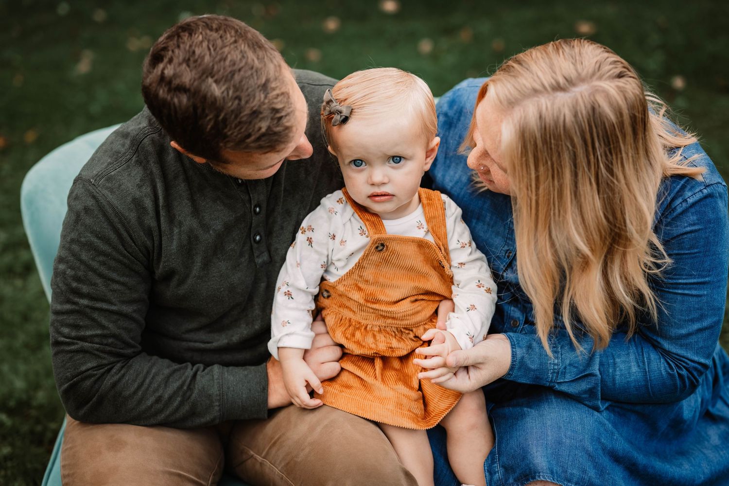 Intimate family moment captured on wooden bench during outdoor photo session.