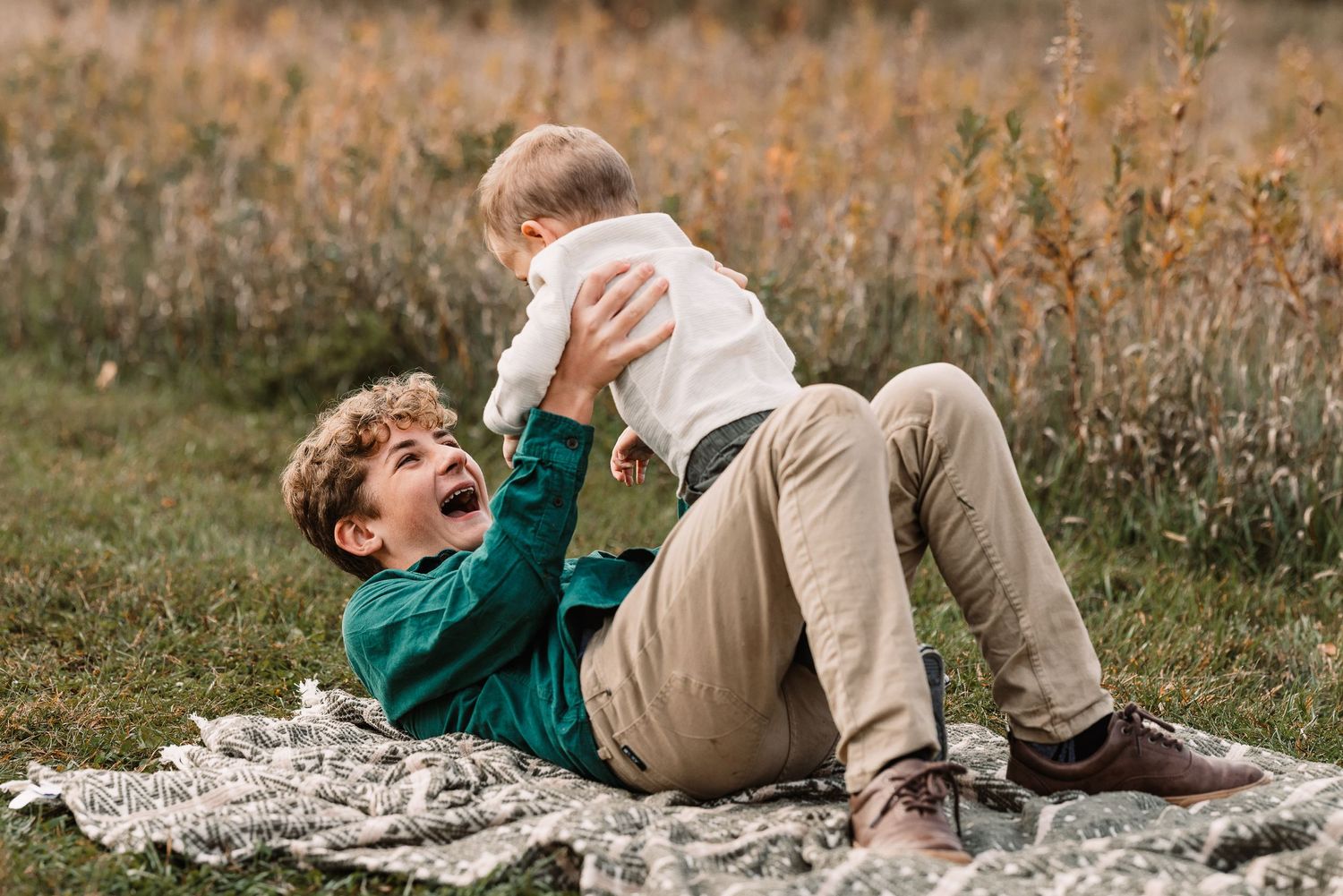 A playful moment captured on a blanket in a field during autumn.