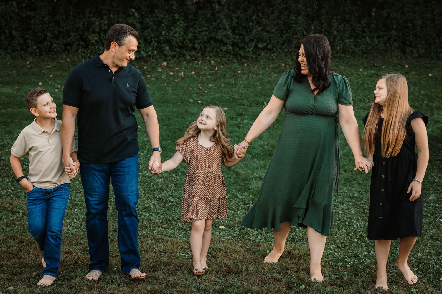 Family walking together and laughing in casual outdoor setting.