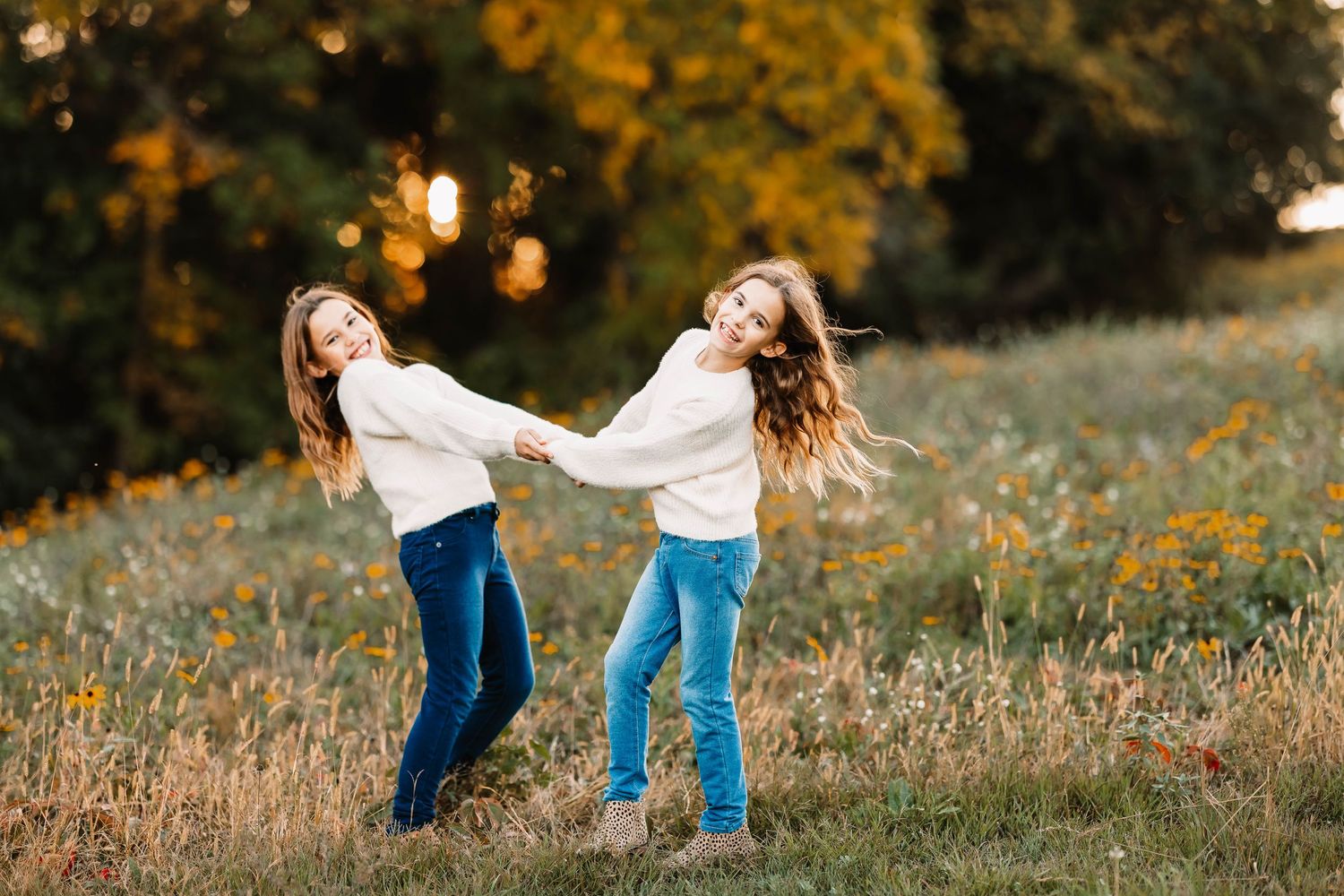 Two young people joyfully playing and spinning in a field of yellow wildflowers.