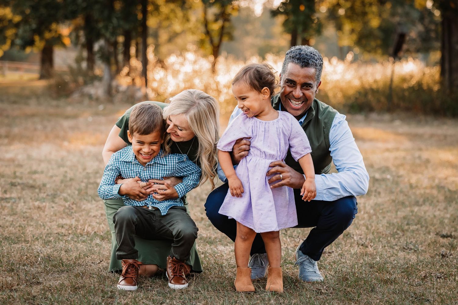 Family shares a joyful outdoor moment together in a sunlit autumn field.
