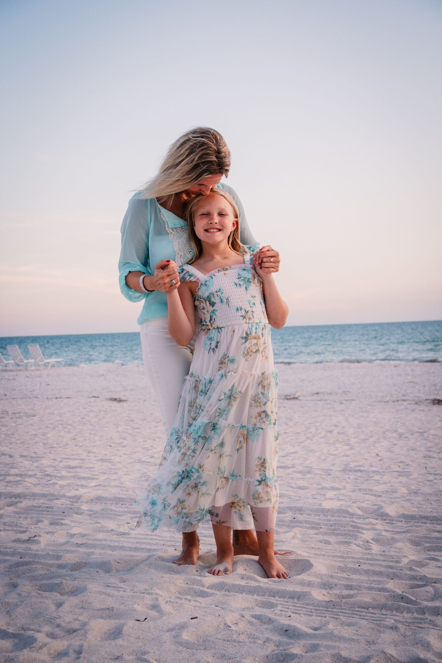 A series of candid beach photos shows sunset scenes with a light blue floral dress against white sand and ocean background.