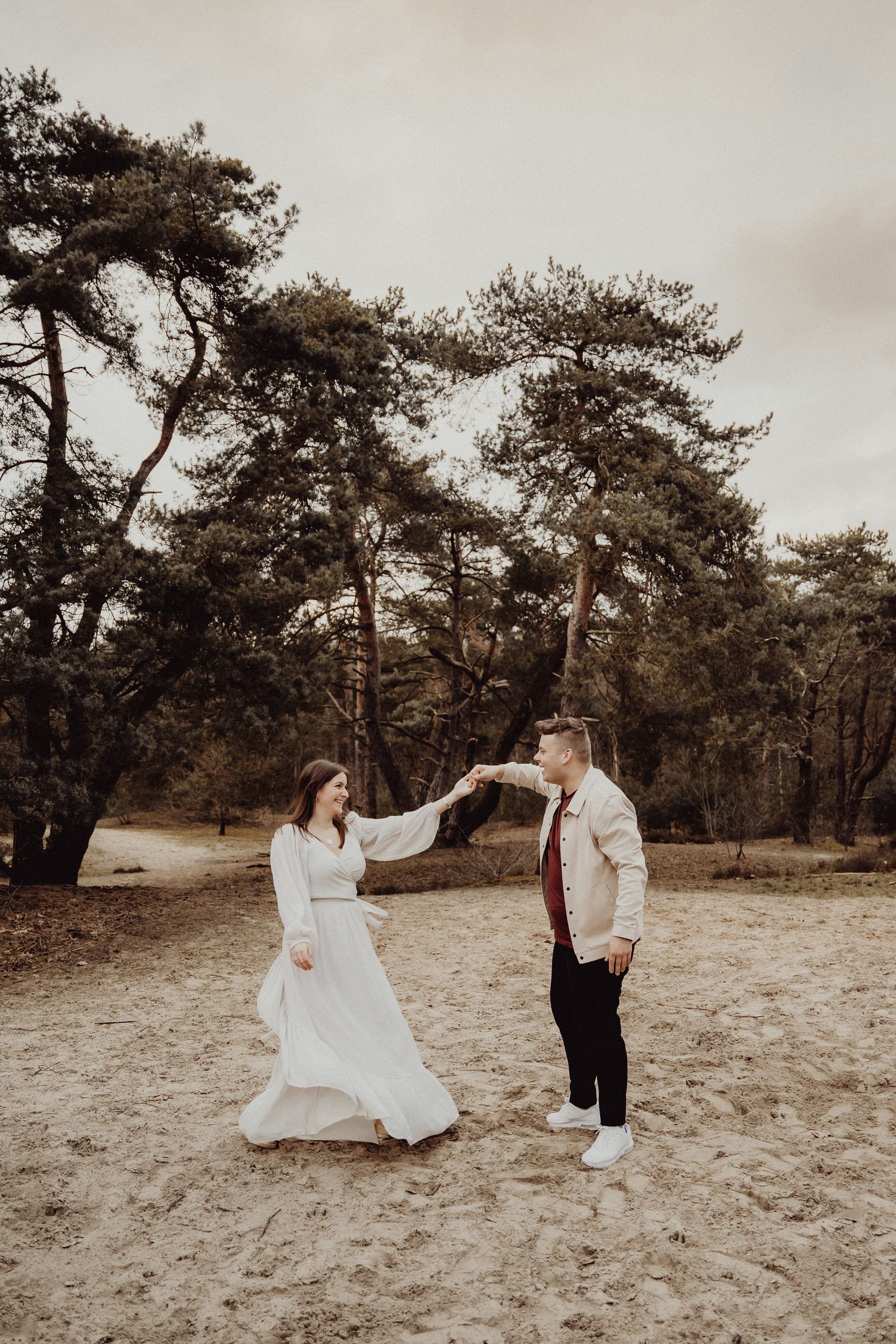 A romantic dance moment captured in a woodland setting with neutral toned clothing.