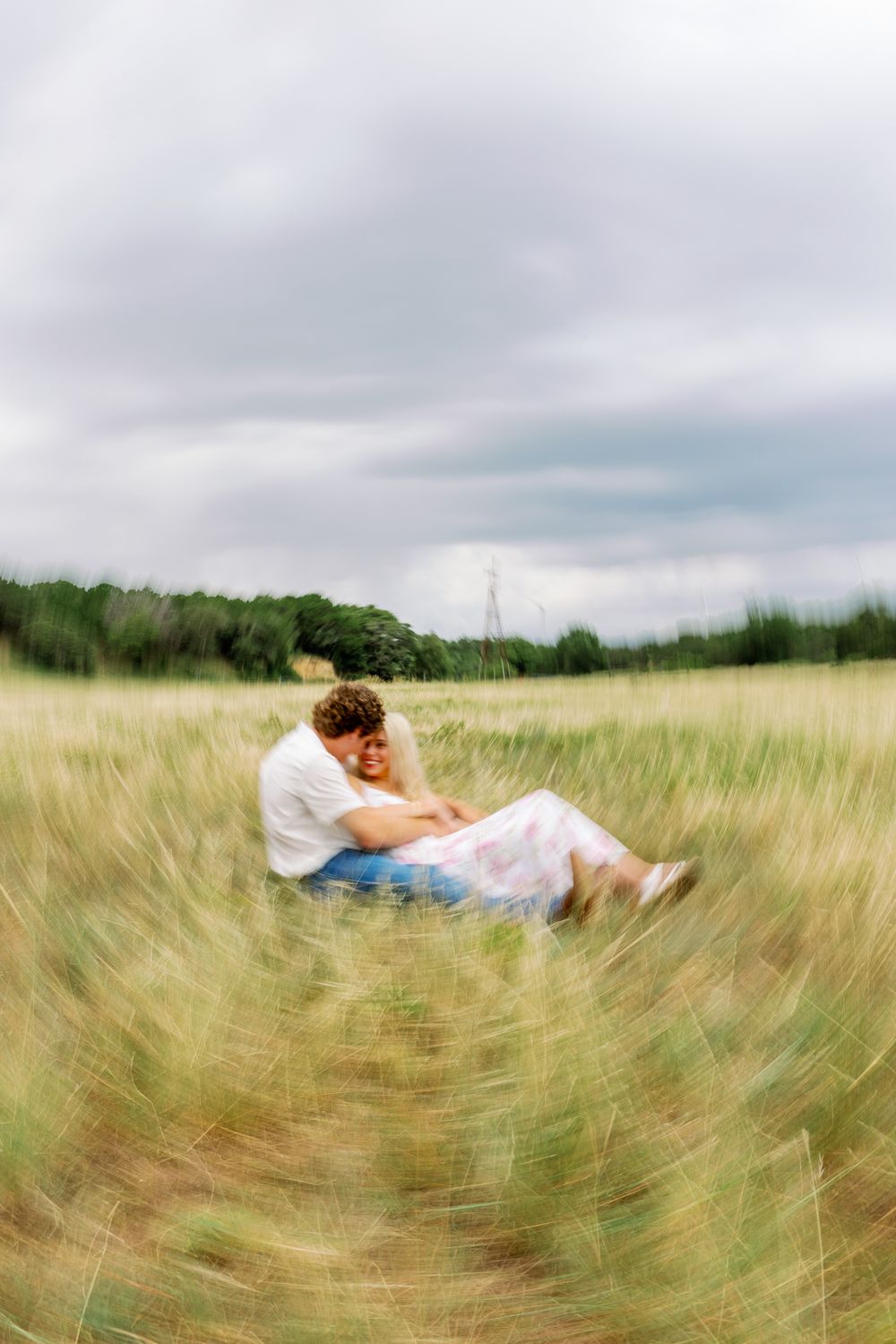 Panoramic field of swaying wheat on a cloudy day showing a figure resting peacefully among the golden stalks.