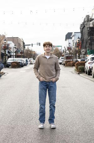 Cora Emilie Media Person standing in middle of city street wearing casual beige sweater and jeans.