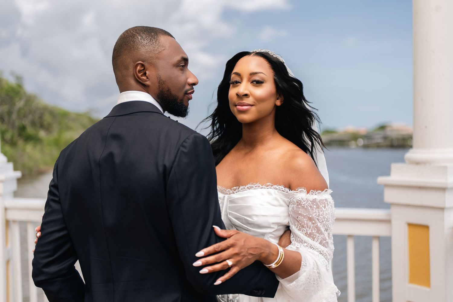 Romantic couple embraces on a garden bridge at sunset during their wedding day.