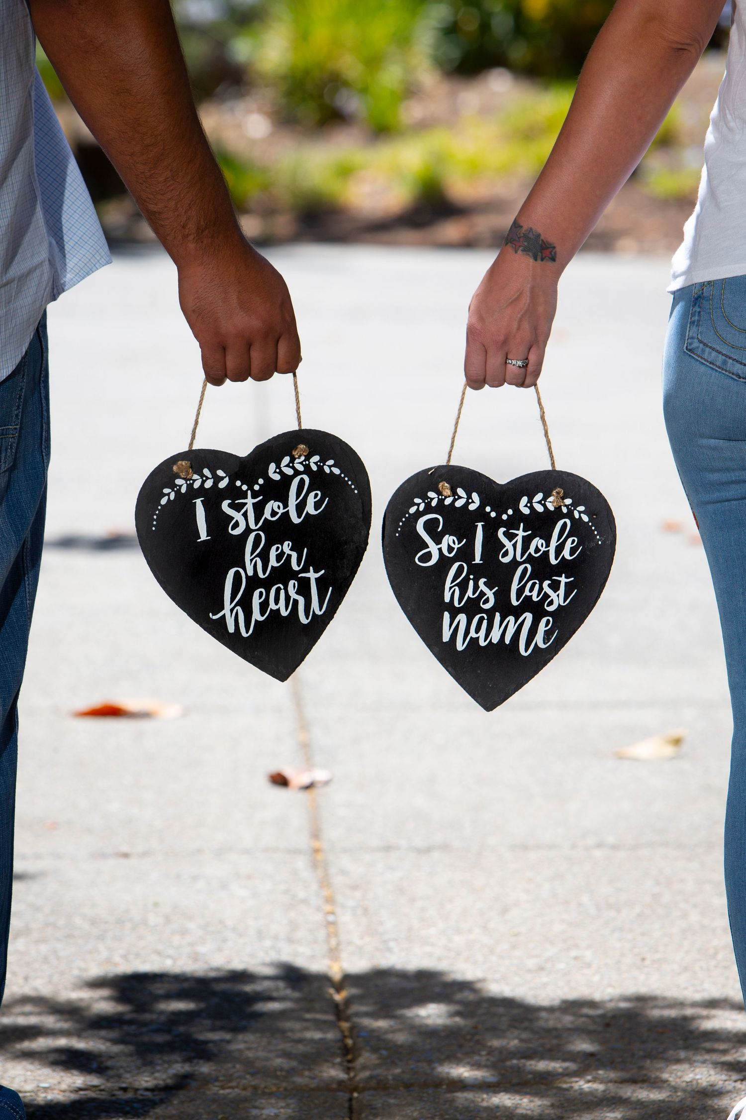Heart-shaped chalkboard signs with romantic messages being held up in outdoor setting.