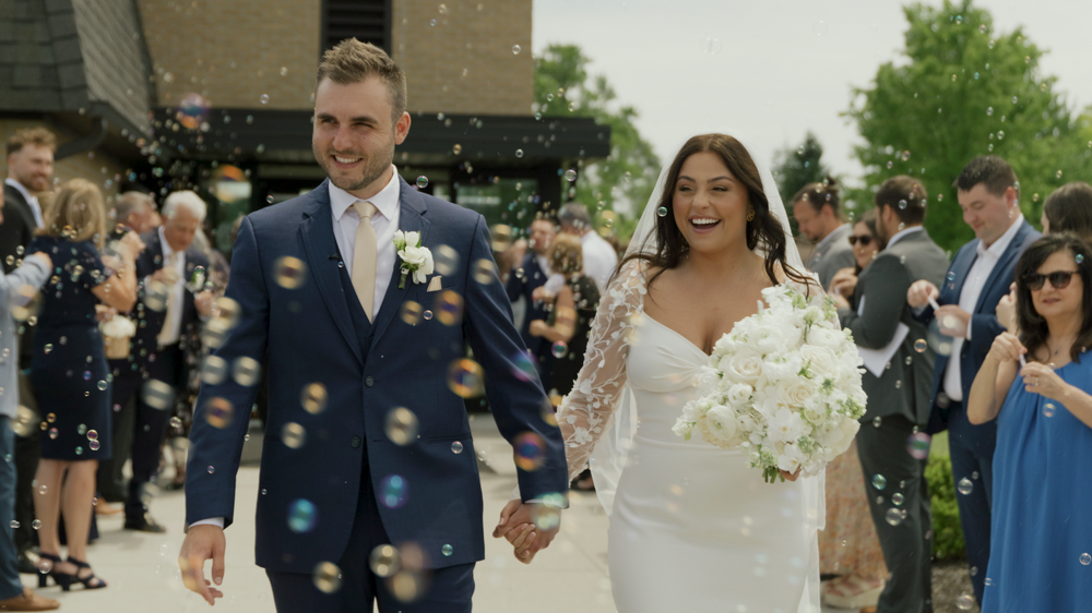 Newlyweds exit ceremony while guests throw confetti in celebration.