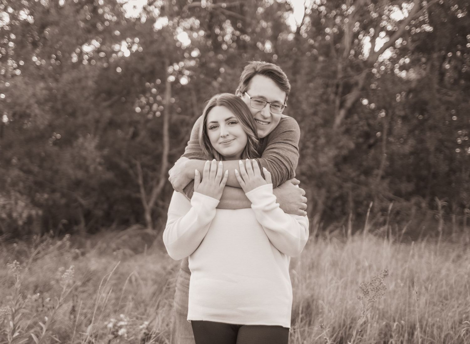 couple in love, man lovingly wrapping arms around his girlfriend, outdoor image, fall time.