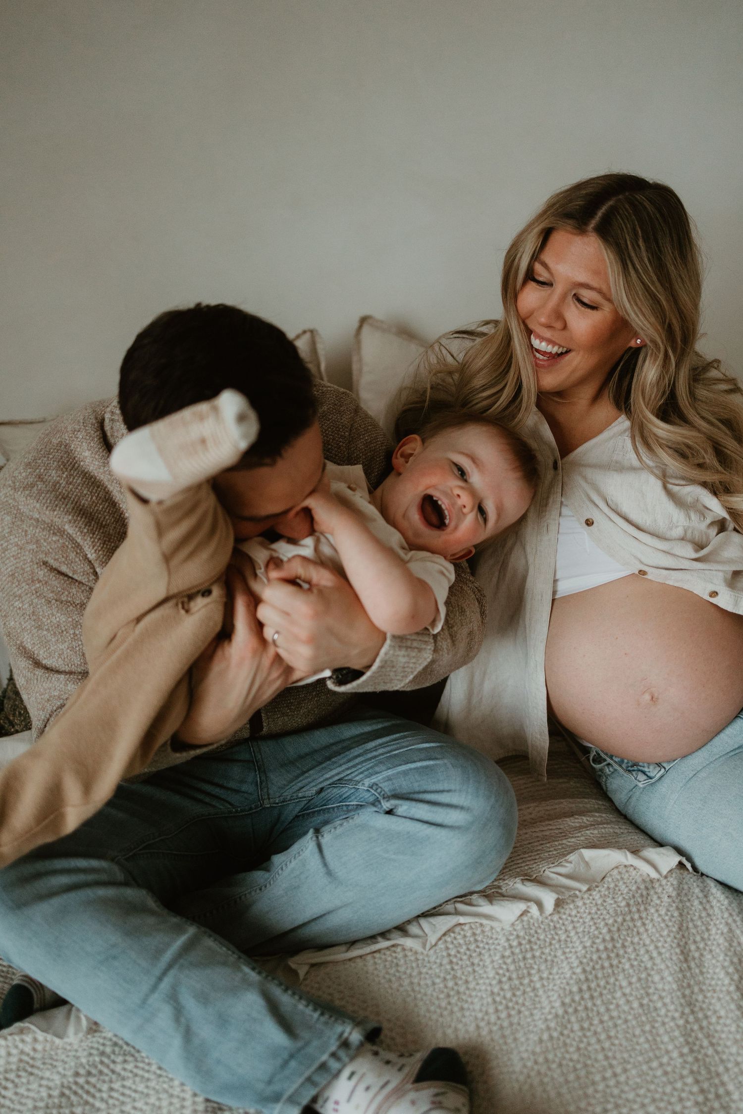 Intimate lifestyle photos of expecting couple sharing joyful moments on bed.