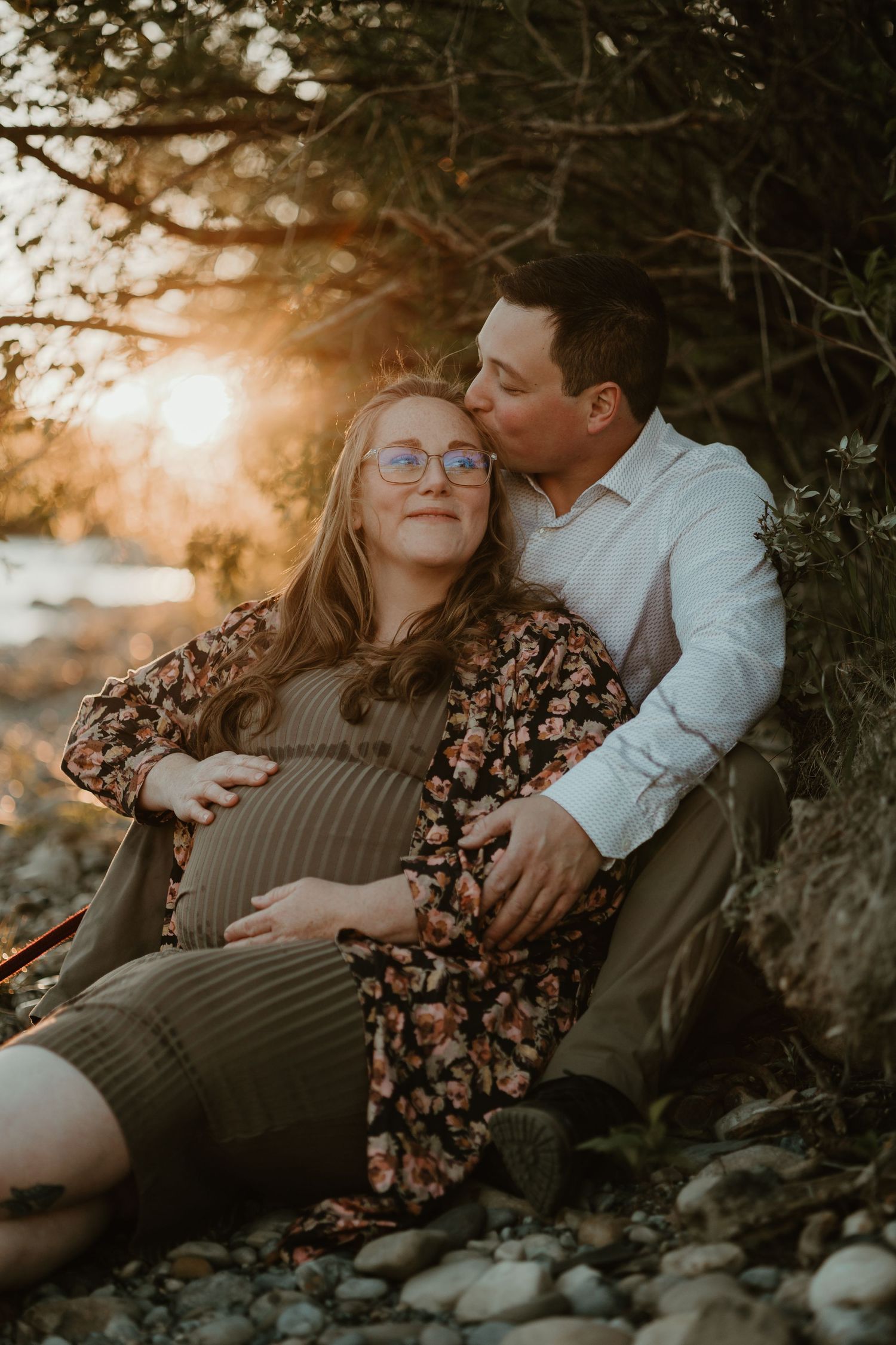Couple relaxing outdoors during sunset maternity photo session.