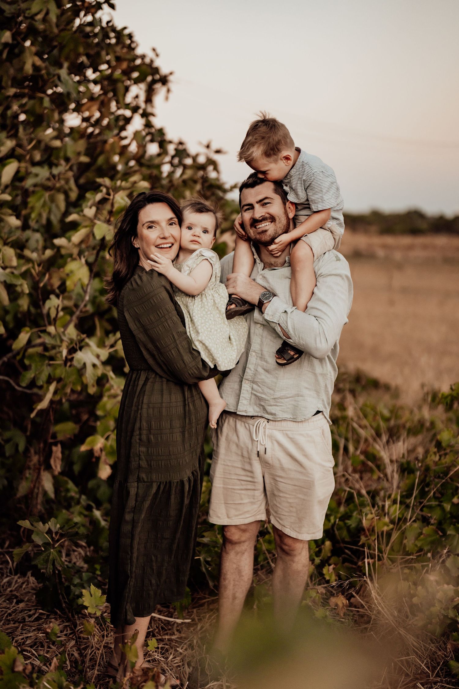 Family enjoying tender moments together in a rustic outdoor setting during golden hour.