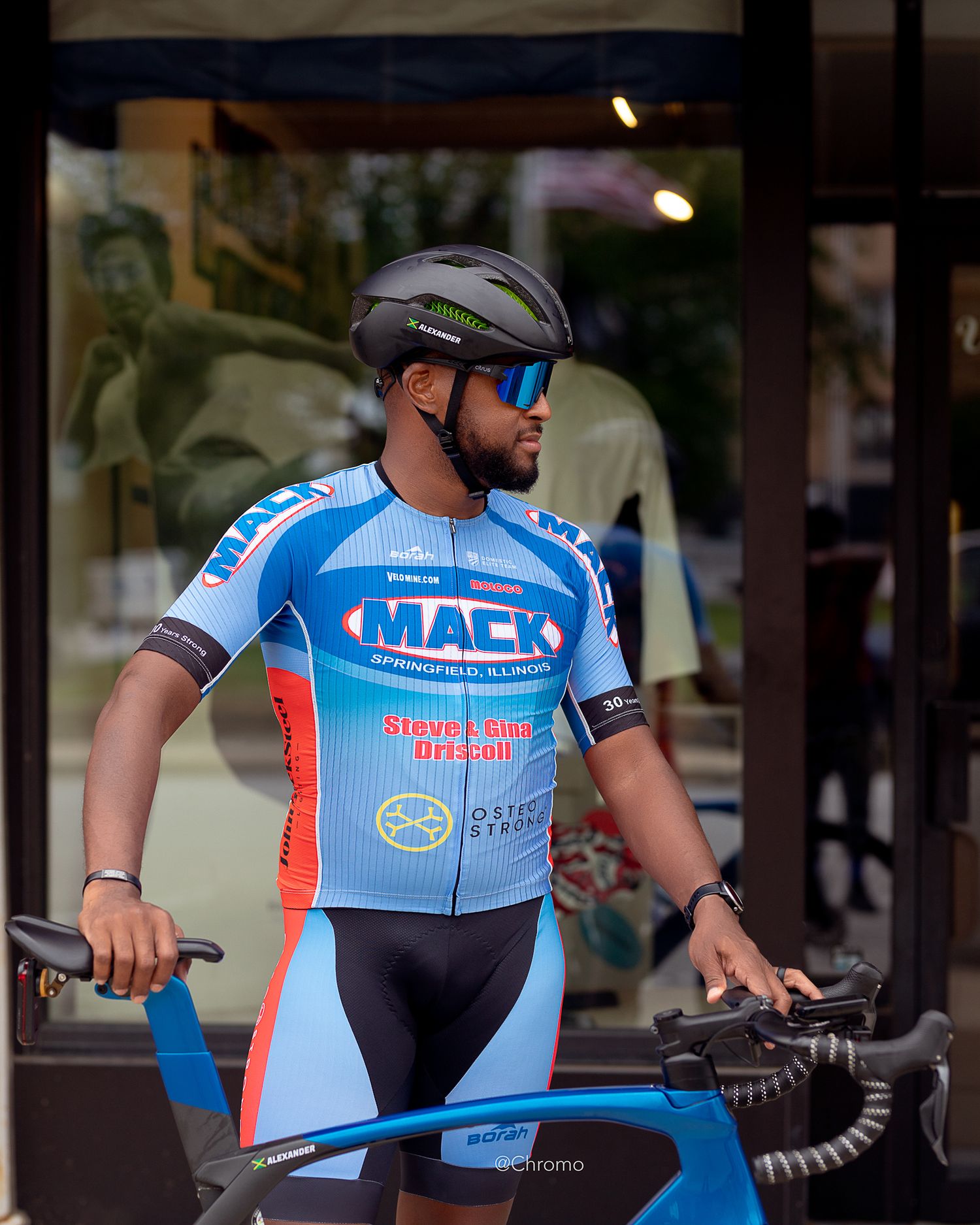 A cyclist in blue and red MACK team gear posed with racing bike.