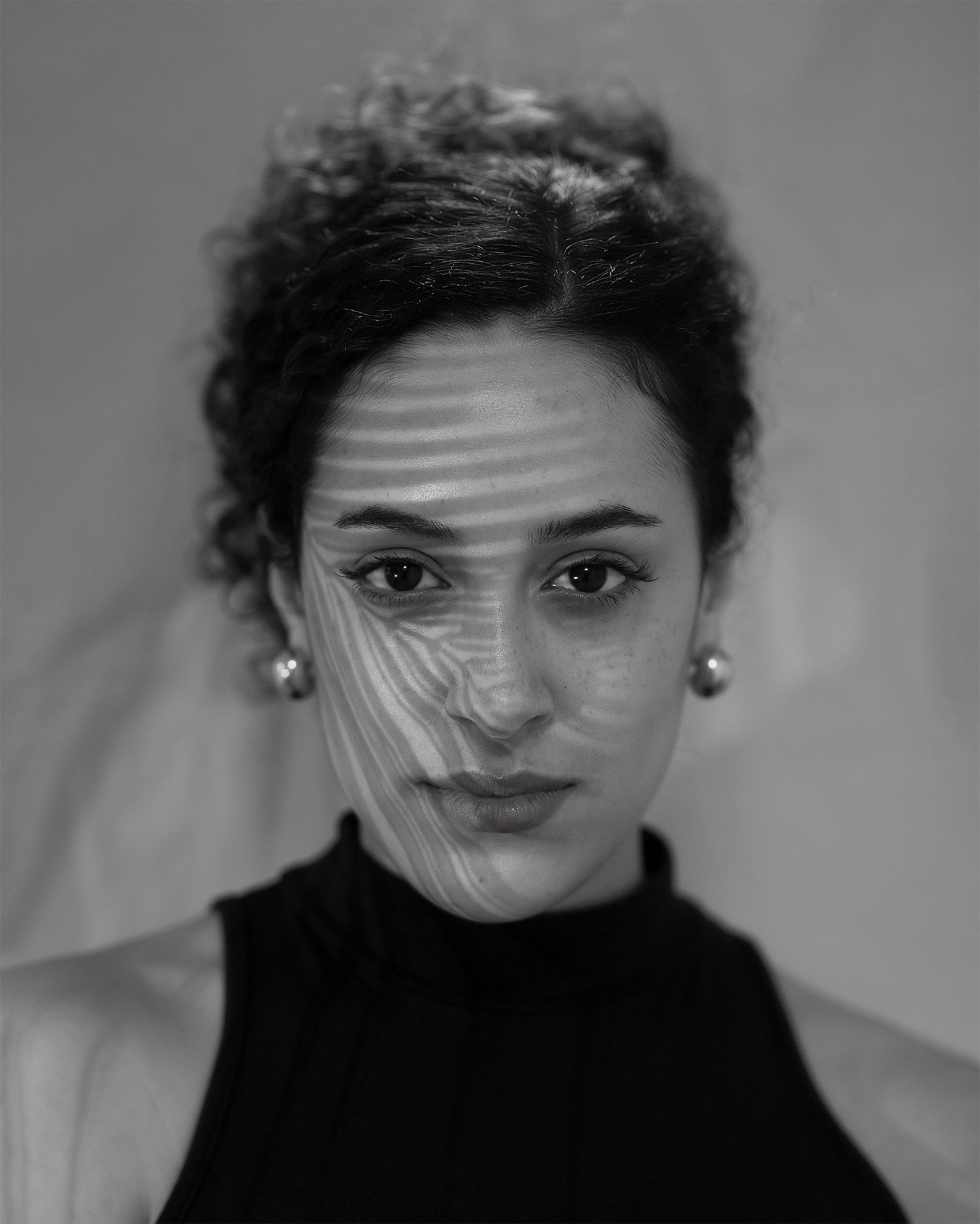 An artistic black and white portrait with unique lighting and geometric shadows.
