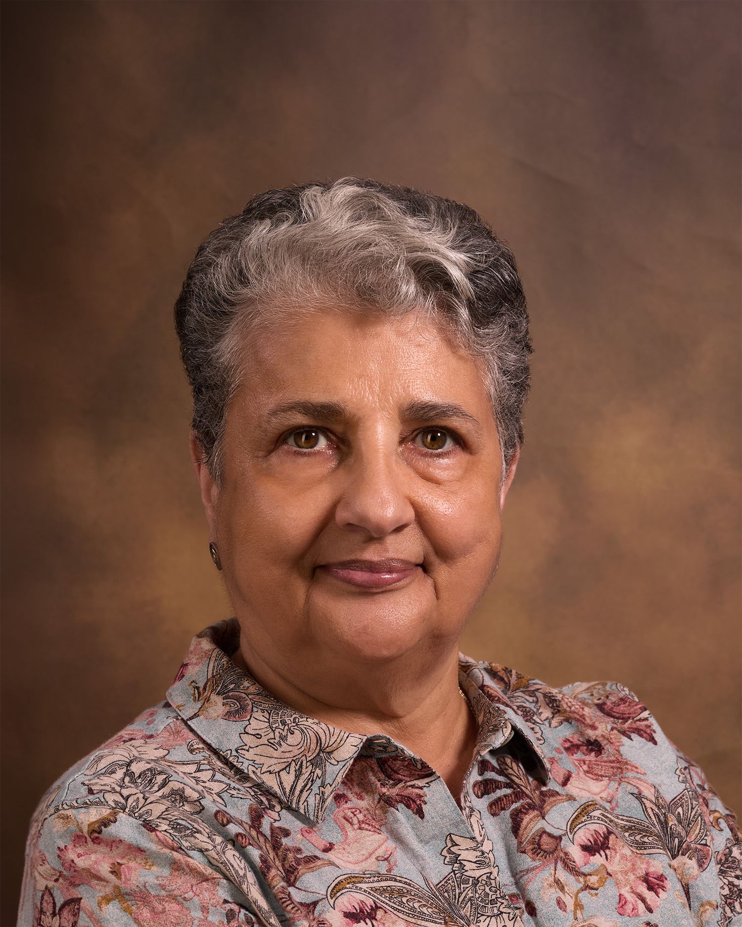 A professional headshot against a brown backdrop.