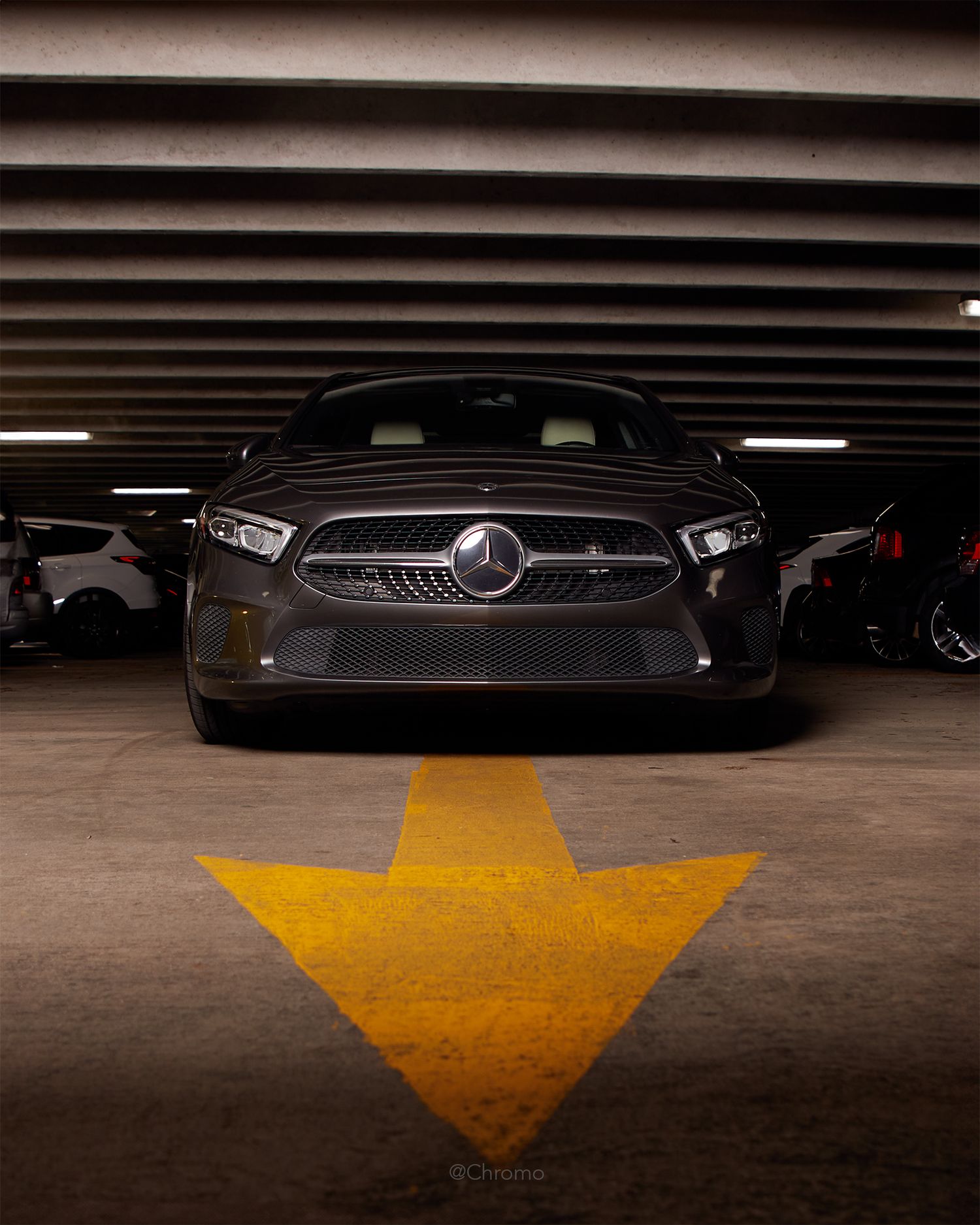 Mercedes-Benz vehicle in a parking garage with yellow directional arrow on floor.